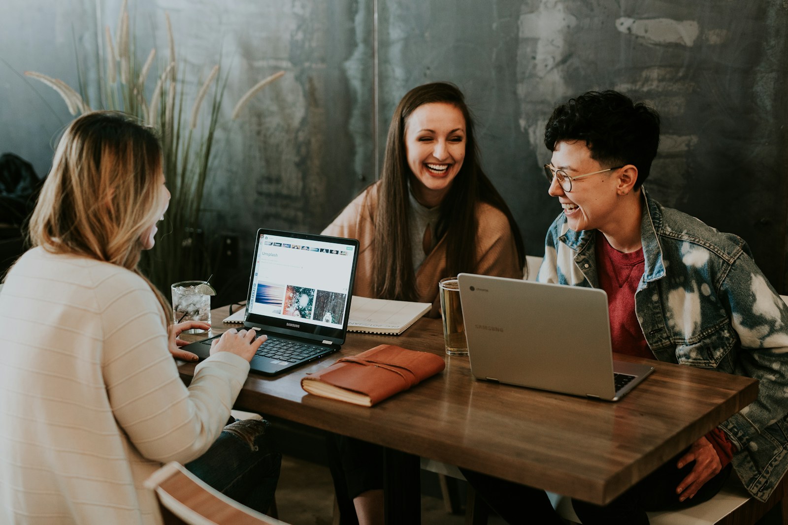 People collaborating around a table with laptops and notebooks